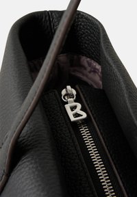 Sac à main en cuir noir texturé avec une fermeture éclair argentée et un charm décoratif en forme de "B". L'intérieur présente une doublure douce de couleur violette.