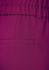 Fuchsia joggers med elastisk midja, med en sidficka och slät textur, som framhäver en livlig färg och minimalistisk design.