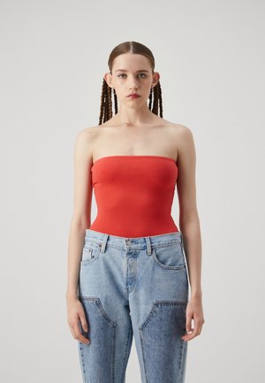 Bodysuit rouge sans bretelles associé à un jean en denim taille haute bleu clair avec des poches au design unique et une coupe décontractée.