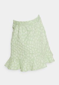 Saia verde floral com bainha franzida, apresentando um tecido texturizado. O design inclui pequenas flores brancas num padrão disperso.