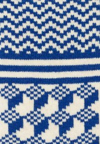 Tessuto a maglia con motivi blu e bianchi, tra cui zigzag, strisce e forme geometriche, con un aspetto testurizzato.