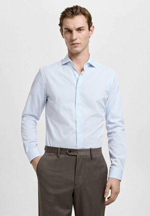 Hellblau gestreiftes Hemd mit Knopfkragen und langen Ärmeln, kombiniert mit dunkelgrauen Hosen mit flacher Vorderseite und Taschen.