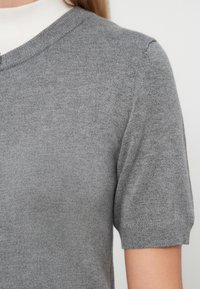 Sivkasta pletena majica s kratkimi rokavi in okroglo ovratnikom, ki prikazuje gladko teksturo in subtilne rebraste detajle na rokavih.