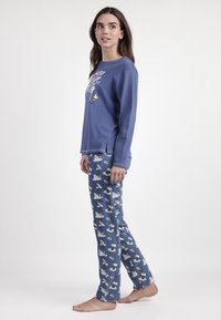 Conjunto de pijama azul que incluye una camiseta de manga larga con un diseño gráfico y pantalones estampados con osos polares sobre un fondo azul oscuro.