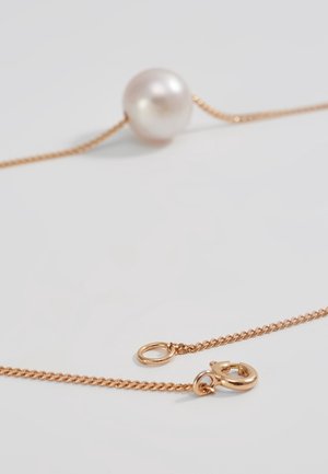 Gouden kettinghalsketting met een enkele grote witte parel en een veerring sluiting, gelegd op een wit oppervlak.