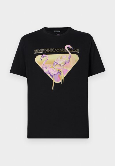 Juodas medvilnės marškinėliai su spalvinga grafika, vaizduojančia du flamingus geltoname trikampyje, o viršuje auksinėmis raidėmis pateikiamas užrašas "EMPORIO ARMANI".