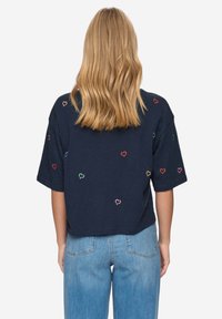 Camiseta corta azul marino con corazones bordados de colores; mangas cortas y corte relajado, fabricada con suave algodón.