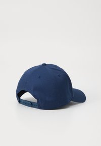 Cappellino da baseball blu navy con una texture di tessuto morbido, visiera curvata, strap plastico regolabile sul retro e un piccolo bottone superiore decorativo.