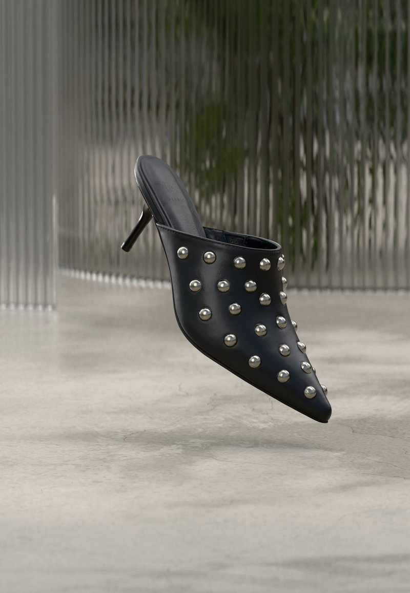 Mule noire à bout pointu avec petit talon, décorée de clous ronds en argent espacés uniformément sur la partie supérieure.