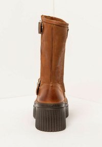 Brown leather ankle boot with a textured black platform sole, featuring a side buckle detail and a smooth finish on the upper section.