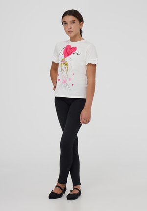 T-shirt bianco con maniche a volant che presenta un'illustrazione di una ragazza, cuori rosa e la parola “Love”. Abbinato a leggings neri e ballerine.