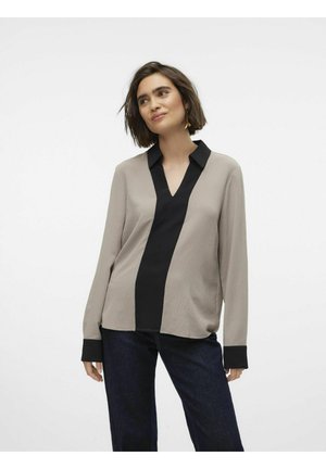Langzaam blouse met lange mouwen in beige en zwart met een opvallende V-halslijn. Beschikt over een contrasterend verticaal paneel en effen zwarte manchetten.