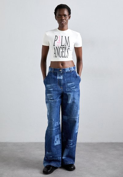 White crop top with black and pink "PALM ANGELS" text; loose blue denim trousers featuring newspaper print; smooth texture, wide-leg design.