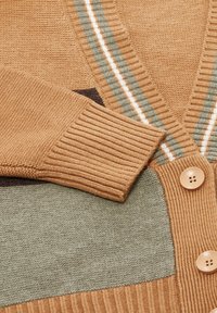 Gehaakte cardigan met beige, groene en bruine kleurvlakken, geribbelde manchetten, gestreepte V-hals en grote beige knoppen.
