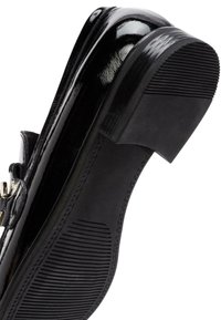 Scarpa in pelle verniciata nera con tacco largo e suola in gomma texturizzata; presenta una fibbia argentata sul lato superiore.