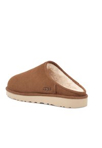 Bruine suède instapslippers met een zachte, crèmekleurige bontvoering, een lichtgewicht beige rubberen zool en subtiele merklogodetail.
