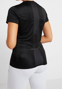 Svart atletisk t-shirt med korta ärmar, med ett nätpanel på baksidan och en slank, figursydd design. Mjuk, elastisk tyg.