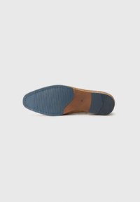 Suela de zapato con forma redondeada. Presenta una base marrón, un patrón de agarre texturizado y una sección de goma azul contrastada con marrón claro.