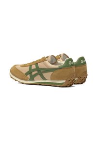 Sneaker beige e verdi realizzati in materiali scamosciati e sintetici, con una suola testurizzata e un marchio distintivo sul tallone e sul lato.