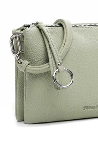 Light green textured leather handbag with silver zipper, ring detail, and detachable strap clip, showing partial brand name "SURI F".