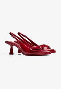 Rote Lackleder-Slingbacks mit spitzer Zehe, Schleifendetail an der Vorderseite und einem einzigartigen, klobigen Absatzdesign.