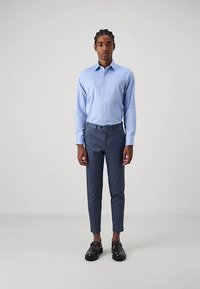 Camicia azzurra chiara con bottoni, pantaloni slim fit blu navy e scarpe nere. Camicia in tessuto liscio, design dei pantaloni affusolato, estetica minimalista.