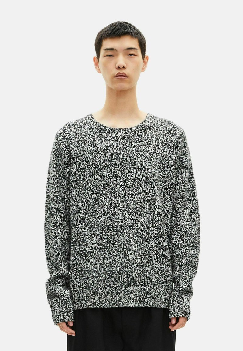 Gebreide sweatshirt in zwart en wit, met een ronde halslijn en lange mouwen met geribbelde manchetten, die een gestructureerd patroon laat zien.