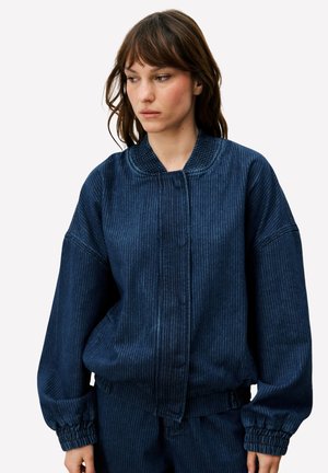 Blauwe corduroy bomberjas met geribde kraag, elastische manchetten en een losse pasvorm. Voorzien van verticale strepen en een ritssluiting aan de voorkant.