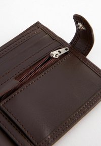 Portefeuille en cuir marron avec plusieurs emplacements pour cartes, un compartiment zippé et des détails cousus. Design compact avec une texture lisse.