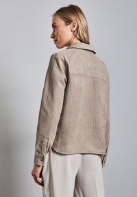 Beige corduroy jacket met een kraag, borstnaad en knoopmanchetten, met een zachte textuur en een relaxed fit.