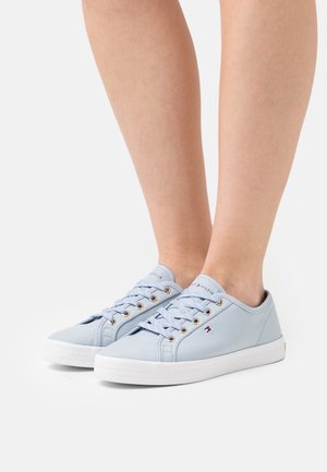 Light blue canvas sneakers with gold eyelets, white rubber soles, and flat laces. Features logo on the tongue and side.
