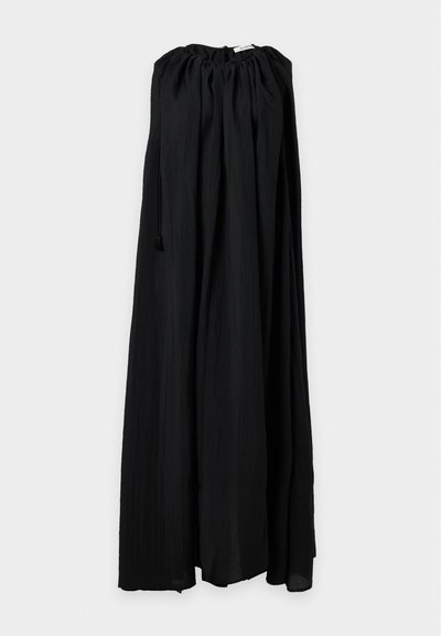 Longue jupe noire avec taille élastique froncée et cordon, suspendue sur un fond clair uni.