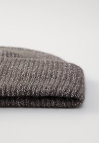 Gorro de punto gris hecho de hilo suave con brillo. Presenta una textura acanalada y un borde doblado, que muestra una forma simple y redondeada.