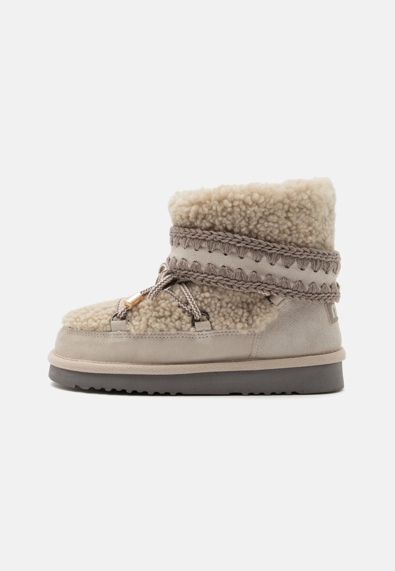 Μπεζ χειμερινή μπότες από shearling με πλεκτή διακόσμηση, δέσιμο με κορδόνια, χοντρή σόλα και απαλό μαλλί που φαίνεται στο πάνω μέρος και στις πλευρές.
