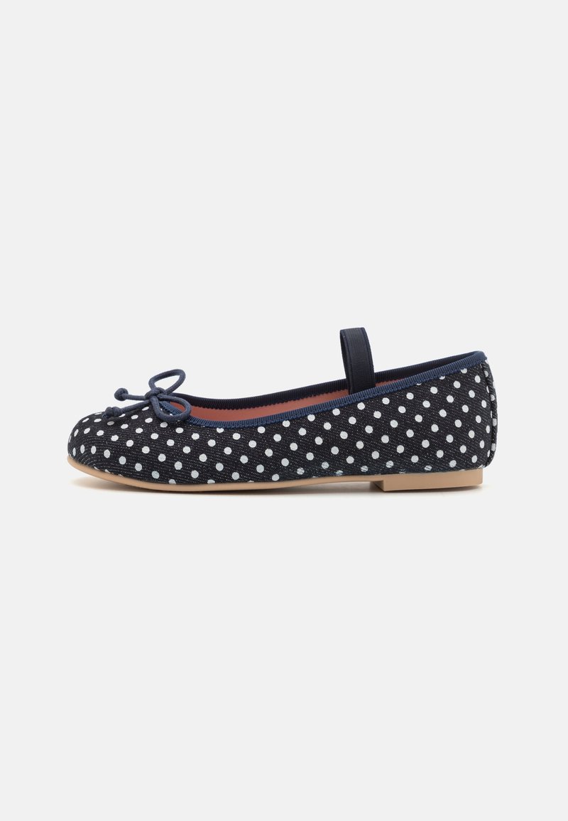 Chaussure de ballet plate bleu marine à pois blancs, un petit nœud sur le devant et une seule sangle élastique sur le coup de pied.