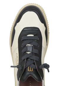Sneaker in pelle bianca e nera con tomaia testurizzata, punta rotonda, lacci piatti e accento del logo dorato. Suola in gomma con bordo testurizzato.