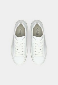 Λευκά δερμάτινα αθλητικά παπούτσια με επίπεδα λευκά κορδόνια, στρογγυλερή μύτη και ανοιχτόχρωμη σόλα. Μαλακή εσωτερική επένδυση. Μινιμαλιστικός σχεδιασμός χωρίς σχέδια.