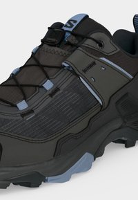 Μαύρο και γκρι outdoor παπούτσι πεζοπορίας με πλεκτό ύφασμα, ρυθμιζόμενο λουράκι, ελαστικά κορδόνια και ανθεκτική ανοιχτό μπλε σόλα για πρόσφυση.