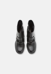 Bottes de cheville en cuir noir avec un bout arrondi, une fermeture éclair sur le côté et des accents de boucle décorative. Semelle texturée avec des détails de couture. Taille 37.