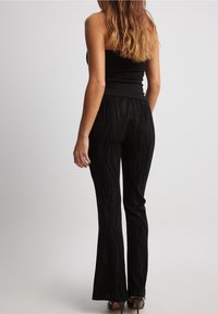 Zwarte flared broek met een glinsterend zebra patroon, gemaakt van een gestructureerde stof. Heeft een middelhoge taille en een slim fit bij de heupen.