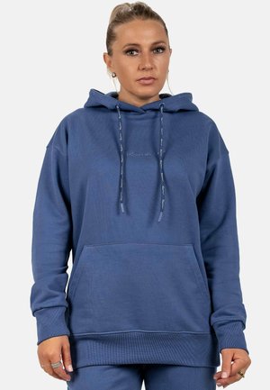 Haut à capuche bleu en tissu doux, avec une poche avant, un capuchon à cordon de serrage et des poignets côtelés. Détail de logo discret sur la poitrine.