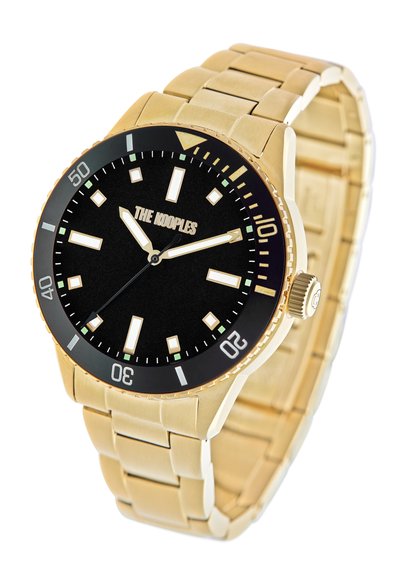 Reloj de metal dorado con esfera negra, marcadores de hora luminiscentes y un bisel unidireccional. Presenta una pulsera texturizada y una corona en el lateral.