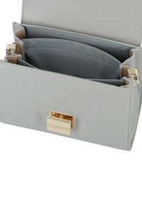Borsa in pelle grigia con una texture liscia, chiusura in metallo dorato e numerosi scomparti interni foderati con tessuto a contrasto.