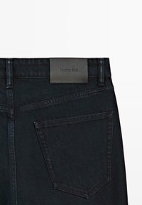 Jeans in denim nero con etichetta a toppe sulla vita sul retro con "Massimo Dutti". Include una tasca posteriore singola di forma appuntita.