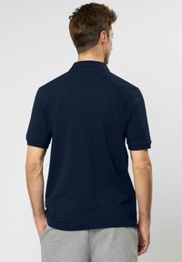Marineblauwe polo met een klassieke kraag, korte mouwen en een rechte zoom. Gemaakt van een zachte, gestructureerde katoenen mix.