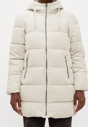 Beige gevoerde corduroy winterjas met ritssluiting aan de voorkant, twee met rits afsluitbare zakken en een verstelbare capuchon, gedragen door een persoon met een donkere huid.