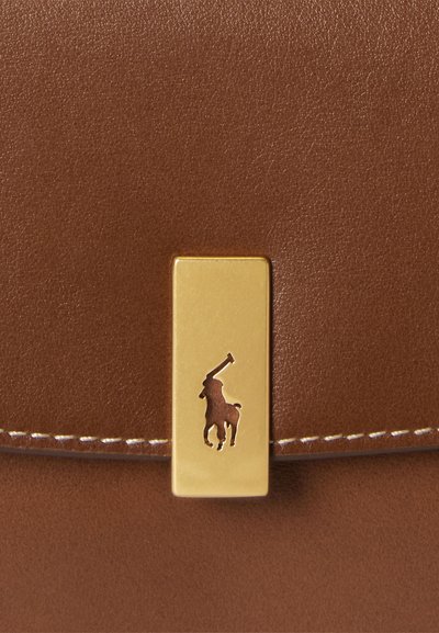 Bolso de cuero marrón con un broche rectangular dorado, con un logo grabado de un jugador de polo en la parte frontal. Textura suave y diseño sencillo.