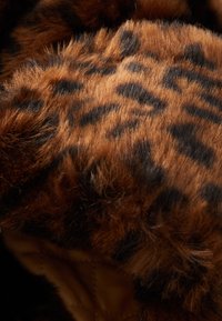 Hnědá umělá kožešina s leopardím vzorem, která má hladkou strukturu a směs světlých a tmavých hnědých tónů.