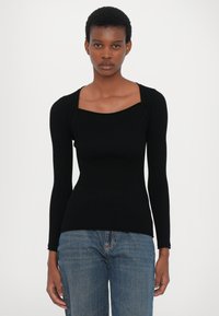 Svart ribbestrikket langermet topp med firkantet utringning. Stoffet har en glatt tekstur, og passformen er kroppsnær gjennom overkroppen.