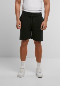 Shorts en coton noir avec une taille élastique et un cordon de serrage, dotés de poches latérales et d'un logo discret sur l'ourlet.